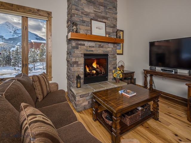 living room featuring a stone fireplace, a mountain view, and light wood-type flooring