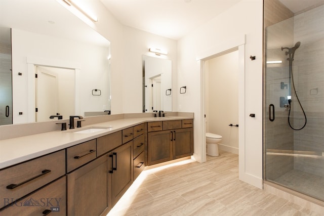 bathroom featuring tile patterned floors, toilet, a shower with door, and double sink vanity