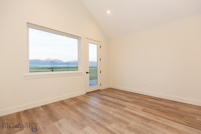 spare room featuring a wealth of natural light, light wood-type flooring, and high vaulted ceiling