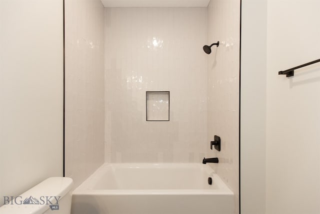 bathroom featuring tiled shower / bath combo and toilet