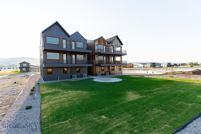 rear view of property with a balcony and a lawn