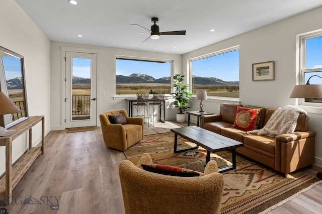 living room featuring a mountain view, ceiling fan, plenty of natural light, and wood finished floors
