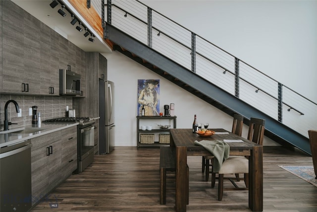 dining space featuring sink, dark wood-type flooring, and a towering ceiling