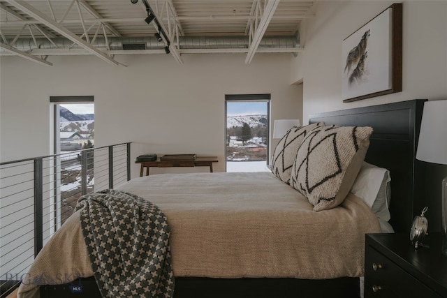 bedroom featuring multiple windows and a towering ceiling