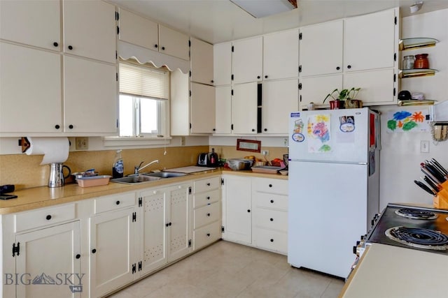 49 Two Dot Hwy, Harlowton, MT 59085 - kitchen with a sink, freestanding refrigerator, white cabinetry, light countertops, and light tile patterned floors