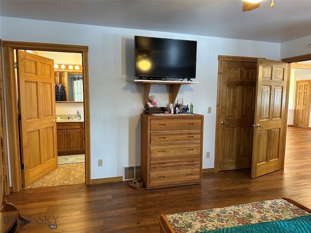 bedroom featuring dark hardwood / wood-style flooring, ceiling fan, ensuite bath, and sink