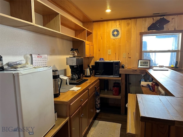 kitchen with built in desk, wooden counters, dark wood-type flooring, and wood walls