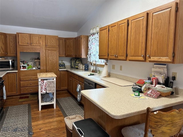 kitchen featuring lofted ceiling, dishwasher, a kitchen breakfast bar, sink, and dark hardwood / wood-style flooring