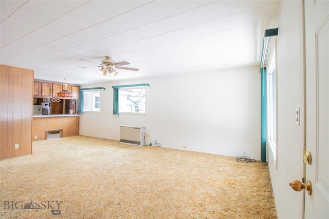 unfurnished living room with ceiling fan, radiator heating unit, and light carpet