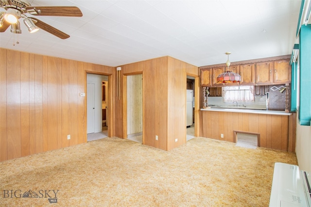 kitchen featuring wood walls, white fridge, ceiling fan, and light colored carpet