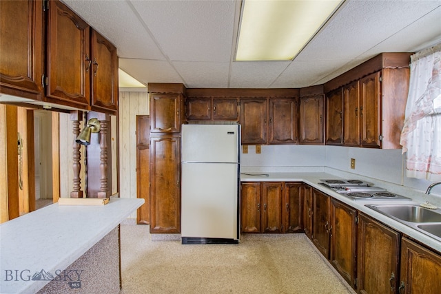 kitchen featuring white refrigerator, light carpet, sink, a paneled ceiling, and stainless steel gas stovetop