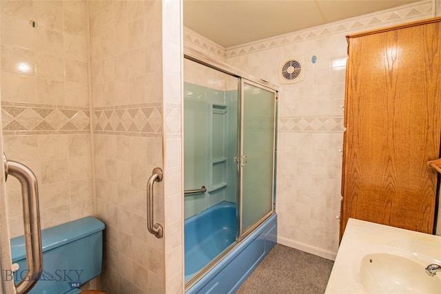 full bathroom with tile walls, toilet, bath / shower combo with glass door, and sink