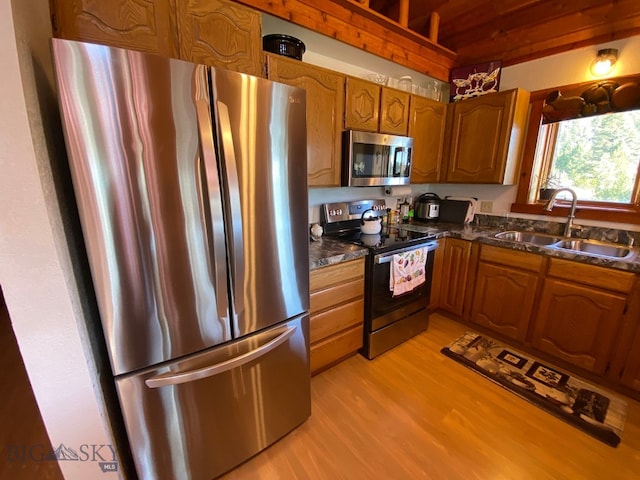 kitchen with dark stone counters, light hardwood / wood-style floors, sink, and stainless steel appliances