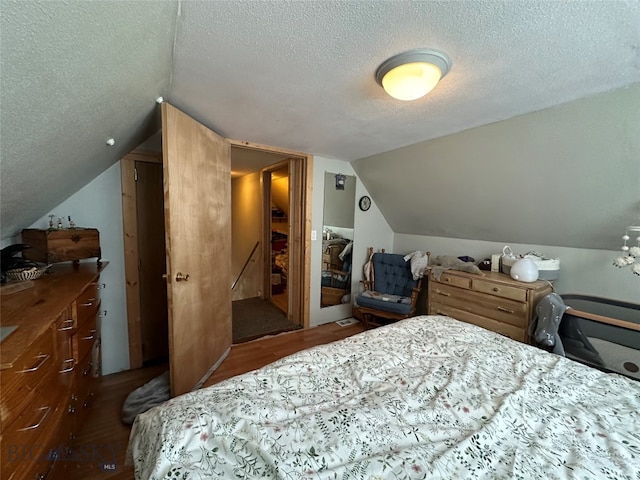 bedroom with lofted ceiling, a textured ceiling, and dark wood-type flooring