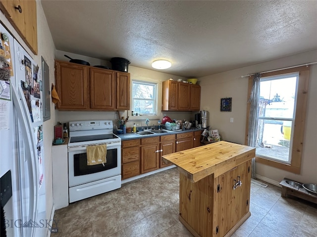 kitchen with white appliances, a healthy amount of sunlight, sink, and light tile floors