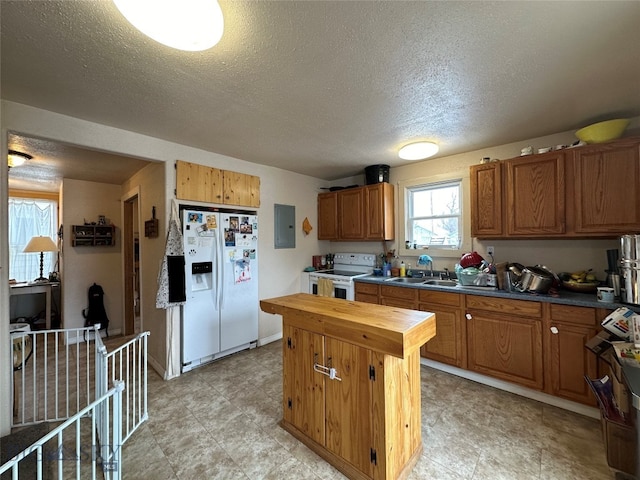 kitchen with a textured ceiling, white appliances, light tile floors, and butcher block countertops