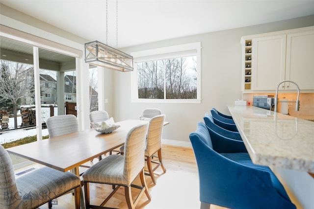 dining space with light hardwood / wood-style floors and a notable chandelier