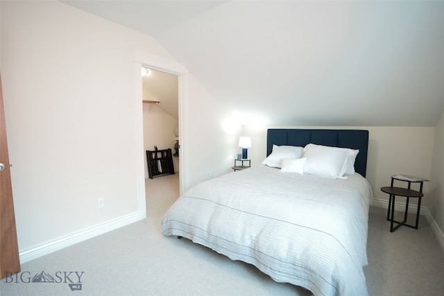 bedroom with a walk in closet, light colored carpet, and lofted ceiling