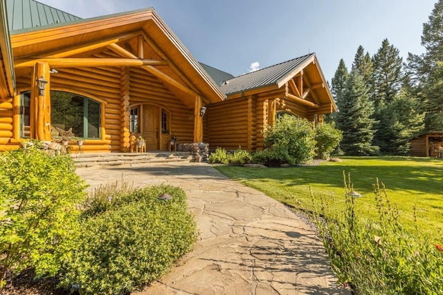 entrance to property with a yard, a standing seam roof, metal roof, and log siding