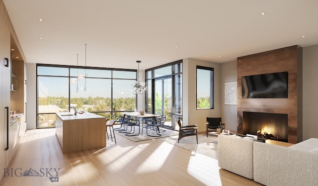 living room featuring expansive windows, a notable chandelier, light wood-type flooring, sink, and a large fireplace