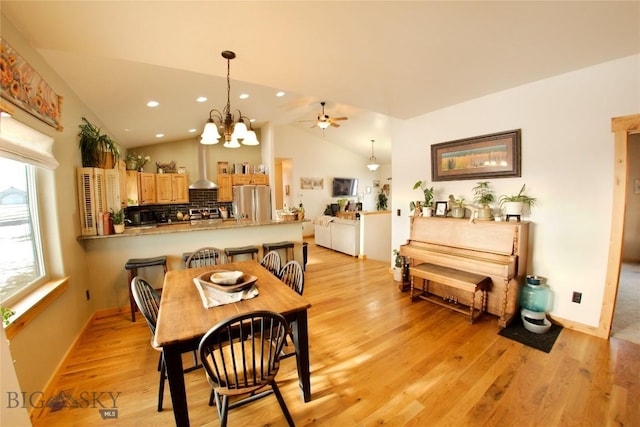 dining room with ceiling fan with notable chandelier, light hardwood / wood-style floors, and lofted ceiling