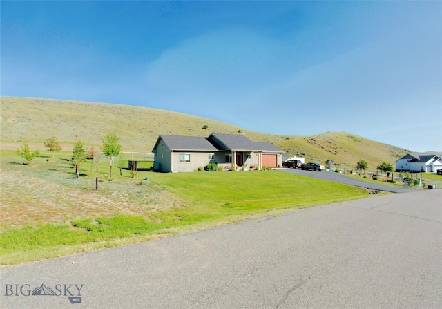 ranch-style home featuring a mountain view, a front lawn, and a garage