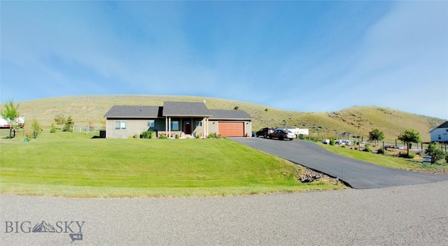 ranch-style home with a mountain view, a front yard, and a garage