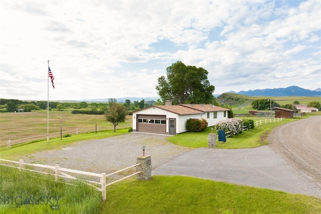 view of front facade with a mountain view, a rural view, a garage, and a front yard