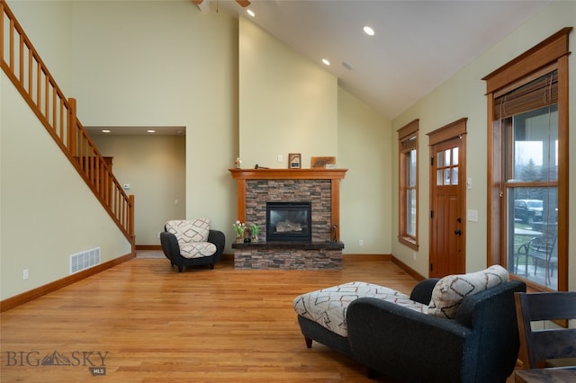 living room featuring a fireplace, high vaulted ceiling, and light wood-type flooring