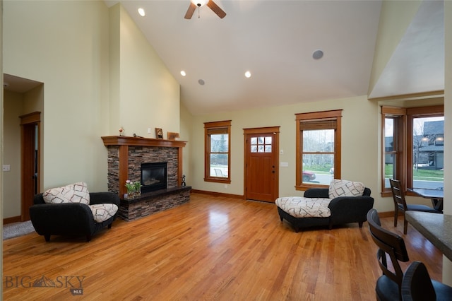 living room with light wood-type flooring, high vaulted ceiling, ceiling fan, and a fireplace