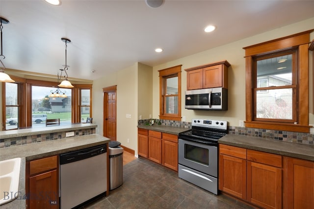 kitchen featuring appliances with stainless steel finishes, dark tile patterned floors, pendant lighting, and a wealth of natural light