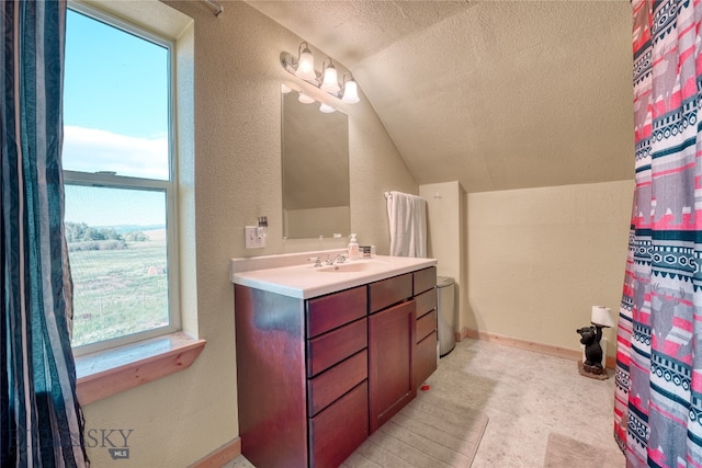 bathroom featuring a textured ceiling, vanity, and lofted ceiling