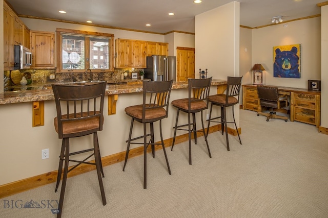 kitchen with appliances with stainless steel finishes, tasteful backsplash, a kitchen bar, stone counters, and light colored carpet