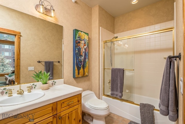 full bathroom featuring tile floors, combined bath / shower with glass door, toilet, and vanity