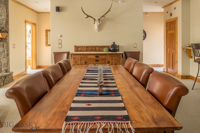 dining space with ornamental molding and light colored carpet