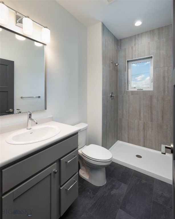 bathroom with tile patterned floors, tiled shower, toilet, and vanity