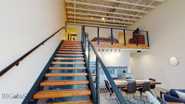 staircase with track lighting and a high ceiling