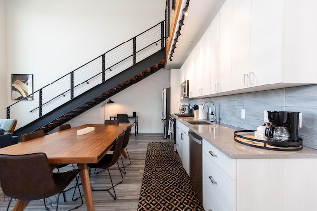 kitchen featuring appliances with stainless steel finishes, backsplash, sink, dark hardwood / wood-style floors, and white cabinets