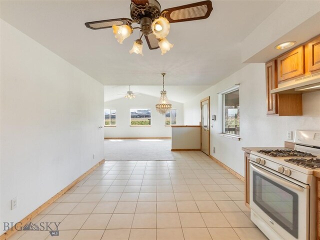 kitchen featuring vaulted ceiling, ceiling fan with notable chandelier, hanging light fixtures, light tile patterned floors, and white gas range oven