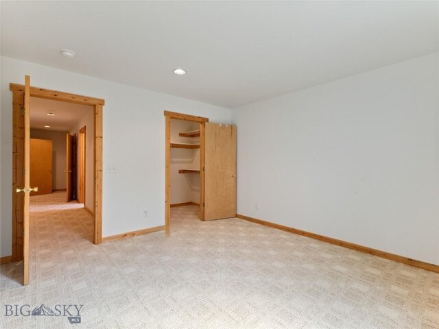 unfurnished bedroom featuring a walk in closet, a closet, and light carpet