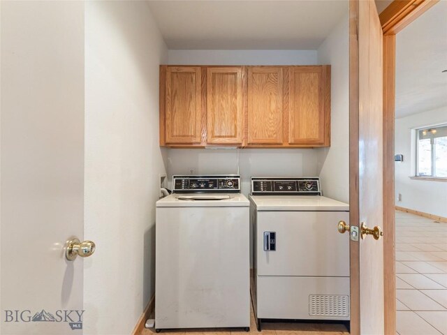 laundry area with cabinets, light tile patterned floors, and washer and clothes dryer