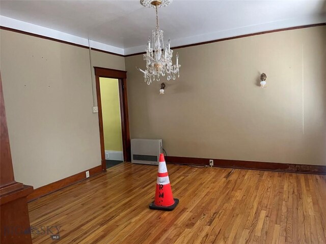 512 W Park, Anaconda, MT 59711 - spare room featuring light wood finished floors, baseboards, heating unit, and an inviting chandelier