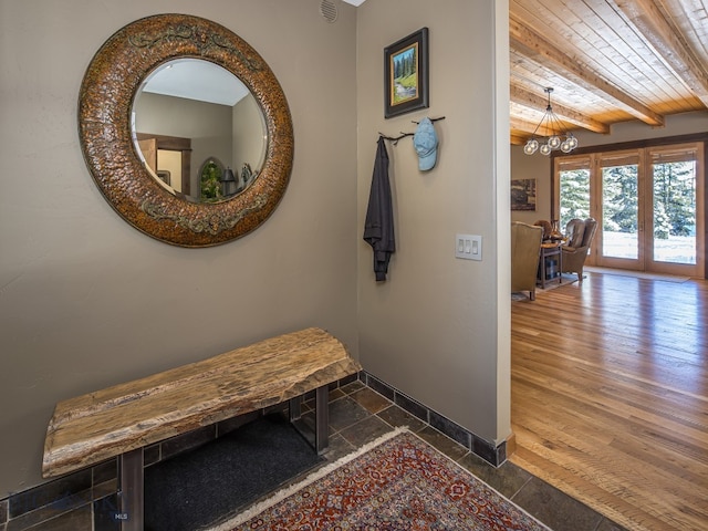 hall featuring beam ceiling, dark wood-type flooring, an inviting chandelier, and wooden ceiling