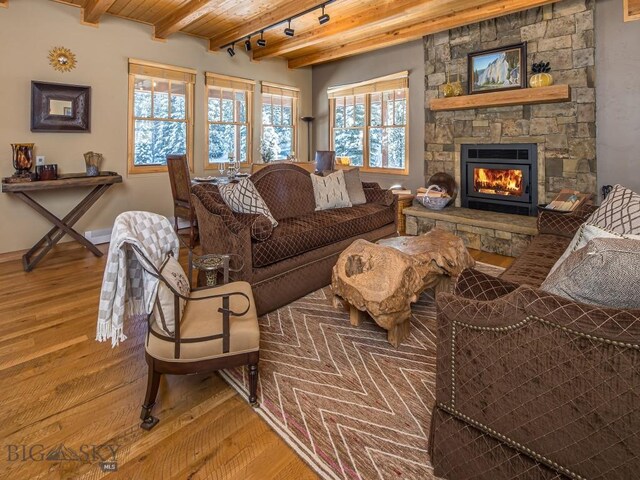 living room featuring wood ceiling, beamed ceiling, track lighting, a fireplace, and wood-type flooring