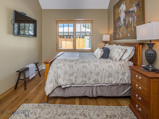 bedroom featuring lofted ceiling, hardwood / wood-style floors, and a baseboard radiator