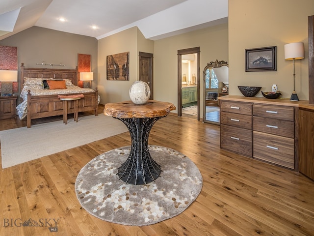 bedroom featuring lofted ceiling, hardwood / wood-style floors, and ensuite bathroom