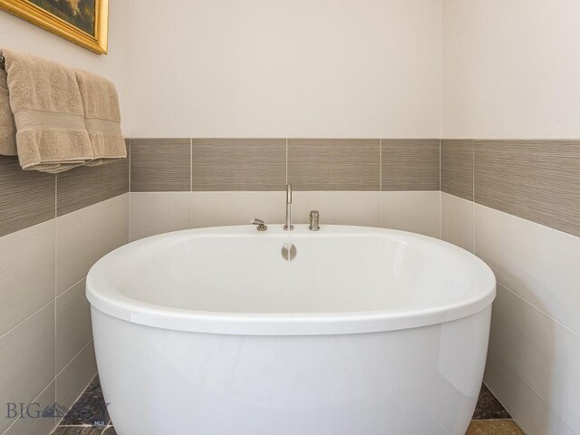 bathroom with tile patterned flooring, tile walls, and a washtub