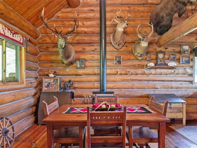 dining room with rustic walls, lofted ceiling with beams, hardwood / wood-style floors, and wood ceiling