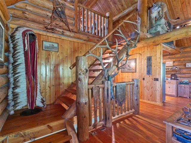 stairway with beamed ceiling, log walls, wooden ceiling, and hardwood / wood-style flooring