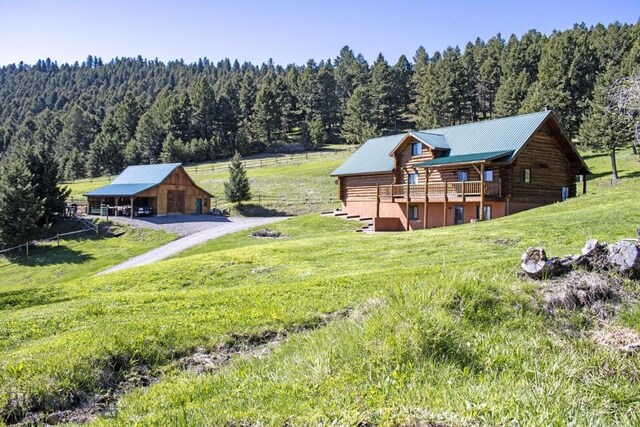 72 Sky Band Trl, Livingston, MT 59047 - back of house featuring a view of trees, log exterior, a lawn, an outbuilding, and a garage